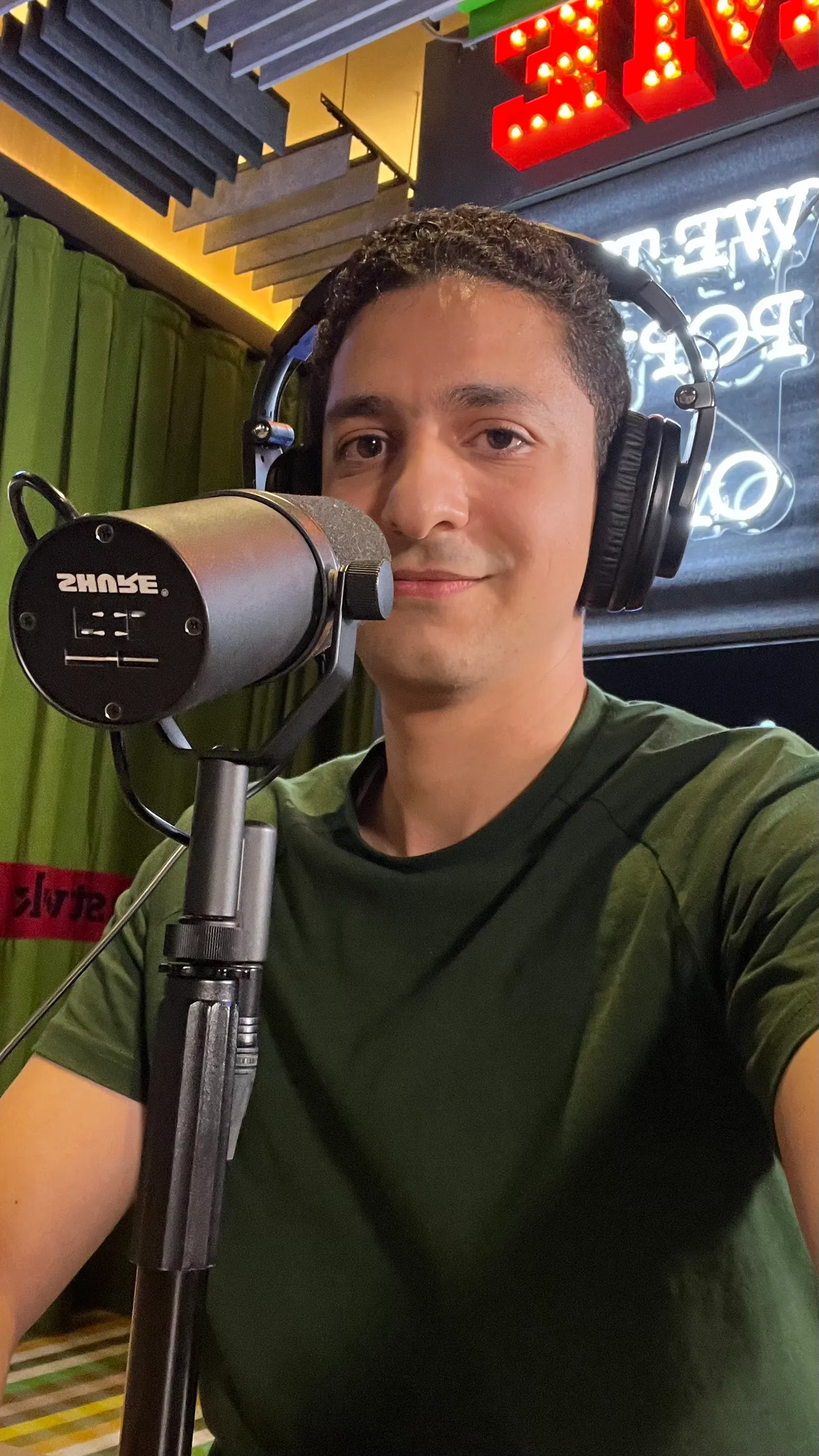 Abdelrahman Ismail wearing headphones at a podcast microphone